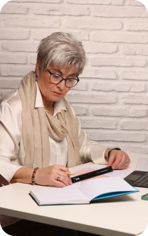 Person am Schreibtisch mit Lineal und Notizbuch bei der Büroarbeit