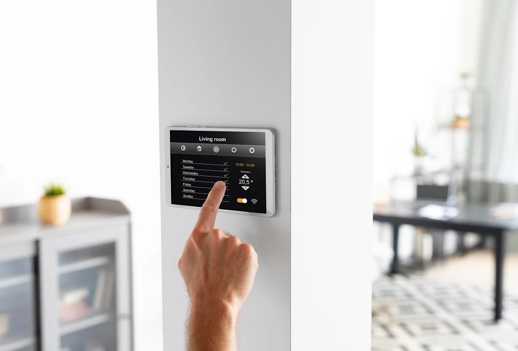 Hand bedient ein Smart-Home-Thermostat-Display mit Wochenplan und Temperaturanzeige 20,5 Grad