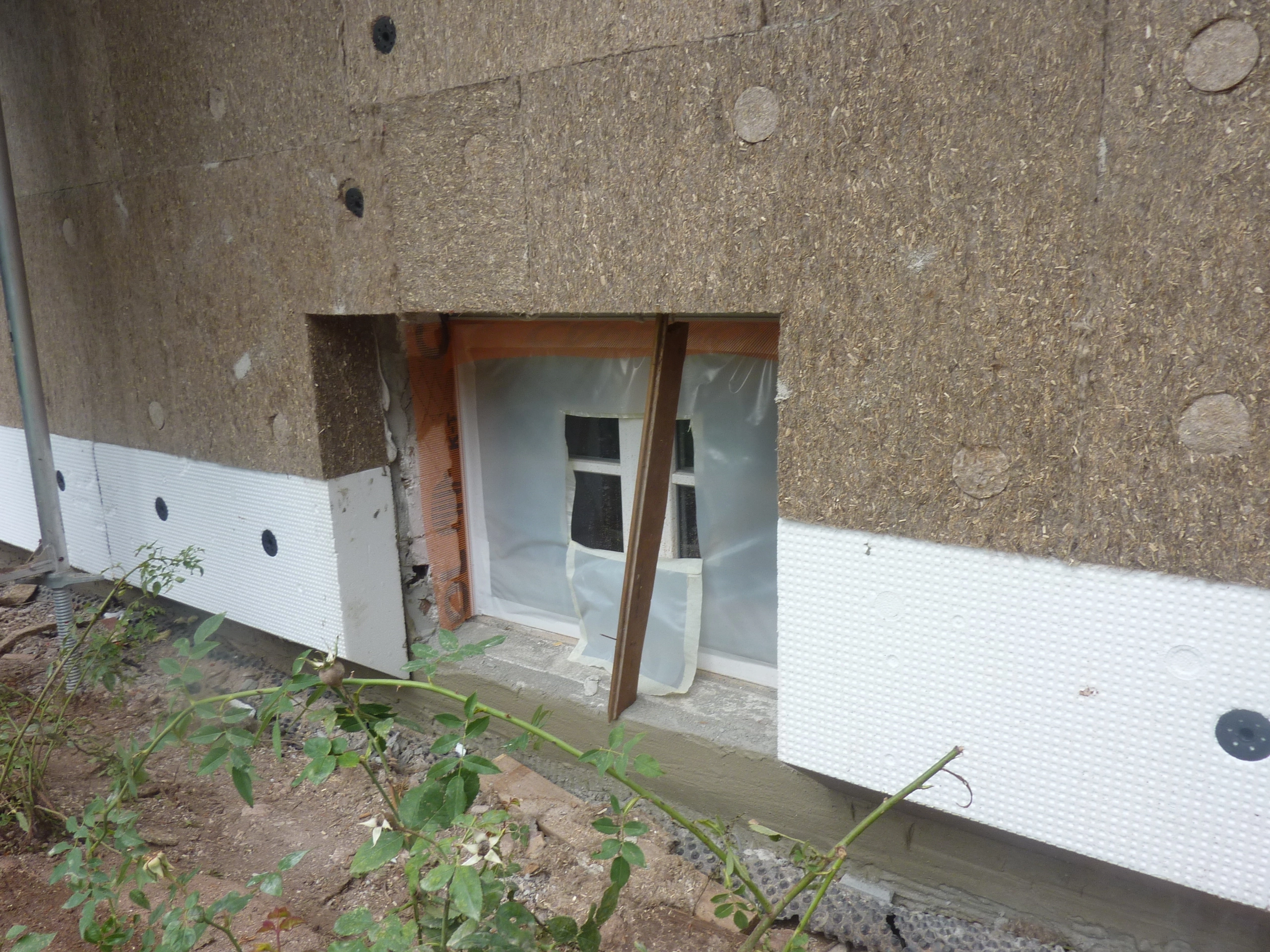 Fassadendämmung mit Holzfaserplatten und Sockeldämmung an einem Fenster im Rohbau
